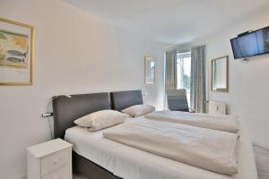 una camera da letto con un letto grande con lenzuola bianche di Residenz Ostseestrand Appartement 4 a Scharbeutz Altre 22 foto