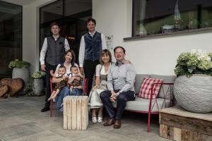 une famille posant pour une photo tout en étant assise sur un canapé dans l'établissement Freina Mountain Lifestyle Hotel, à Selva di Val Gardena