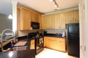 a kitchen with wooden cabinets and a black refrigerator at 1 BR 1BA Oasis Near LSU and Casino Free Parking in Baton Rouge