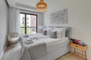 a white bedroom with a large bed and a window at Downtown Apartments Riverside & Parking Szafarnia Street in Gdańsk