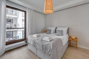 a white bedroom with a bed and a window at Downtown Apartments Riverside Szafarnia Street in Gdańsk