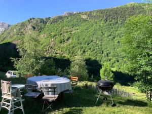 Maison écologique pleine montagne (eco-gite gavarnie) في جيدريه: شواية وطاولة وكراسي امام جبل