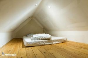 een wit bed op een zolder met een houten vloer bij Maison écologique pleine montagne (eco-gite gavarnie) in Gèdre