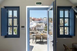 una porta che conduce a un balcone con tavolo e sedie di Acave Santorini Suites a Vóthon