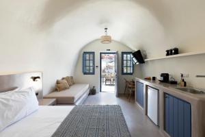 una camera con letto e una cucina con divano di Acave Santorini Suites a Vóthon