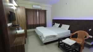 SringeriにあるSTAYMAKER Shubhodaya Lodgeのベッドとテレビが備わるホテルルームです。