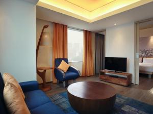 a living room with a blue couch and a television at Mercure Jakarta Simatupang in Jakarta