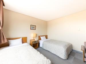 高山市にあるTabist 観光ビジネスホテル松山 飛騨高山のベッド2台と窓が備わるホテルルームです。