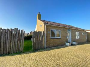 una casa de ladrillo con una valla de madera al lado en Op 't Landtweg 37, en Callantsoog