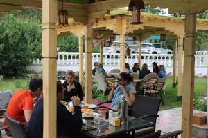 un grupo de personas sentadas en una mesa bajo un cenador en Raku Guest house en Leh