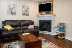 sala de estar con sofá de cuero marrón y chimenea en Whistler Village - Redwood 10 condo, en Steamboat Springs