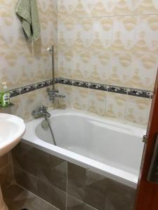 Maliaways Comfy Airbnb-Jkia في نيروبي: حمام مع حوض استحمام أبيض بجوار حوض
