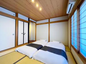 Shirakabanoyado - MINATO, 白樺の宿 - 港, max 10 guests! BBQ OK! في أوساكا: سريرين في غرفة ذات نافذتين +50 صورة