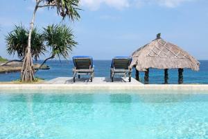 two chairs and a umbrella next to a swimming pool at Villa Lumba Lumba - Oceanfront & Spectacular View! in Nusa Lembongan