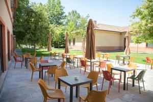 a patio with tables and chairs and umbrellas at Hotel Real Balneario Carlos III in Trillo