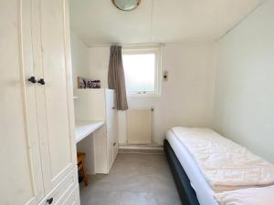 Un dormitorio pequeño con una cama y una ventana. en Op 't Landtweg 37a, en Callantsoog