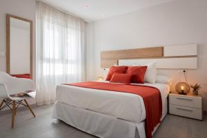 a white bedroom with a large bed with red pillows at Viviendas con Fines Turísticos "Quivir Fleming" in Andújar