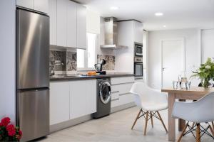 a kitchen with white cabinets and a stainless steel refrigerator at Viviendas con Fines Turísticos "Quivir Fleming" in Andújar +2 photos