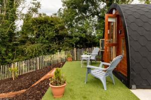 a garden with two chairs and a small shed at Ivy hill Glamping Pod in Ennis
