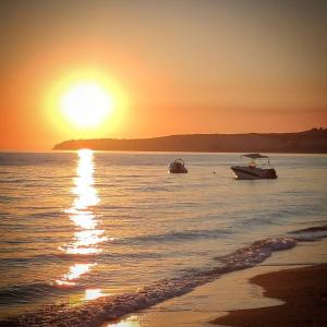 dwie łodzie w wodzie o zachodzie słońca na plaży w obiekcie La Margherita - Casa vacanze w mieście Montallegro