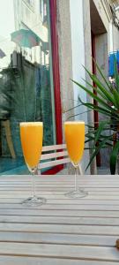 Dois copos de sumo de laranja sentados numa mesa. em Rua Grande Hotel em Viana do Castelo