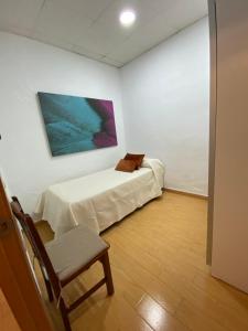 Pokój z łóżkiem, krzesłem i obrazem w obiekcie Amplio Piso en el Centro de Cádiz w Kadyksie