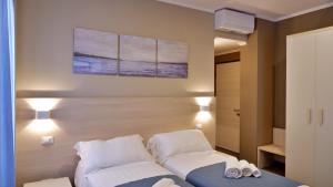 Pianomare Riviera Apartments and Rooms في إمبيريا: غرفة نوم بسرير ووسادتين بيض