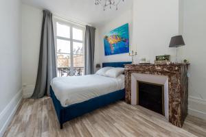 sypialnia z łóżkiem i kominkiem w obiekcie Suites Mana - Bleu Pacifique - Vue sur Place Ducale avec Parking privé inclus w mieście Charleville-Mézières