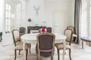 a dining room with a white table and chairs at Suites Mana - Bleu Pacifique - Vue sur Place Ducale avec Parking privé inclus in Charleville-Mézières
