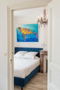 a bedroom with a blue bed and a painting on the wall at Suites Mana - Bleu Pacifique - Vue sur Place Ducale avec Parking privé inclus in Charleville-Mézières