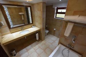 a bathroom with a sink and a mirror and a toilet at Casa Solada Hotel in Kampala