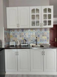 Una cocina con gabinetes blancos y un fregadero. en Rumi place, en Varna