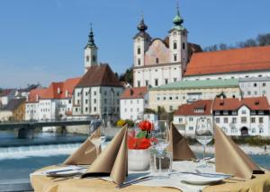 a table with chairs and wine glasses and a city at Hotel-Restaurant Minichmayr in Steyr