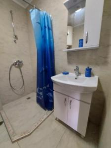 a bathroom with a sink and a shower with a blue shower curtain at Rumi place in Varna City +4 photos