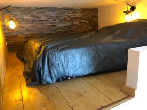 a bed with a black blanket on a wooden floor at appartement 8 couchages au lioran rando vtt ski in Le Lioran