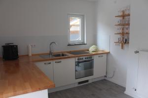 a kitchen with white cabinets and a sink and a window at Ferienwohnung Felgenwald in Michelstadt