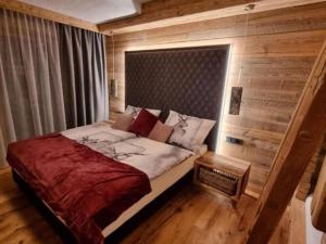 a bed in a room with a wooden wall at Chalet in Großkirchheim Carinthia with sauna in Großkirchheim
