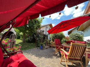 a patio with a table and red umbrellas at Pension Neue Messe in Rackwitz