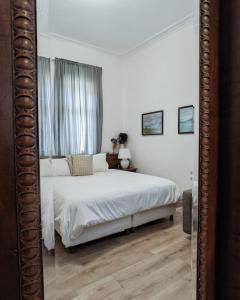 1 dormitorio con cama blanca y espejo en Garden Villa Boutique Hotel, en Pogradec