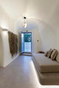 a white room with a bed and a large window at Acave Santorini Suites in Vóthon
