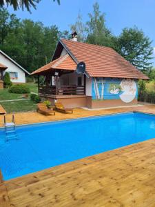 ein Haus mit einem Pool vor einem Haus in der Unterkunft "Garaske Breze" Kućice za izdavanje sa bazenom in Aranđelovac