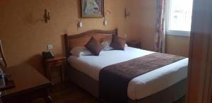 ein Hotelzimmer mit einem Bett mit weißer Bettwäsche und Kissen in der Unterkunft LOGIS HOTEL - Le Relais Saint Vincent in Ligny-le-Châtel