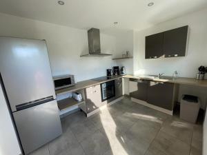a large kitchen with a counter and a refrigerator at Les Balcons de la Vallée in Haybes