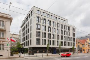 czerwony samochód zaparkowany przed białym budynkiem w obiekcie Moderna Central Luxury Apartment with Parking in Gdynia by Noclegi Renters w mieście Gdynia