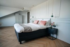 een slaapkamer met een groot bed met roze kussens bij MyHotel Steenwijk - Giethoorn in Steenwijk