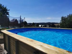 une grande piscine bleue avec une terrasse en bois dans l'établissement FeWo "Waldblick" mit Pool und Kinderspielplatz, à Dippoldiswalde