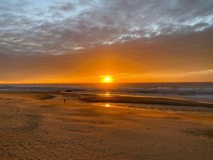 a sunset on a beach with the ocean at Badhotel 316 in Callantsoog +2 photos