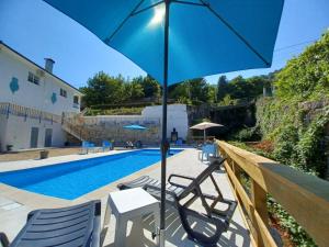 a pool with chairs and an umbrella next to a swimming pool at Waterfalls Gerês AL in Geres