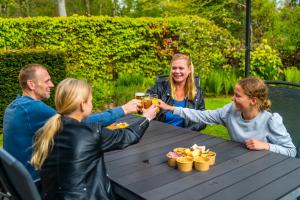 un grupo de personas sentadas alrededor de una mesa con bebidas en Europarcs Koningshof, en Schoorl
