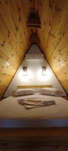 a bed in a room with a wooden ceiling at Valea cu Dor Verde in Pîrscov